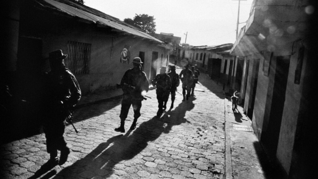 Grupo armado caminando entre calles de un pueblo