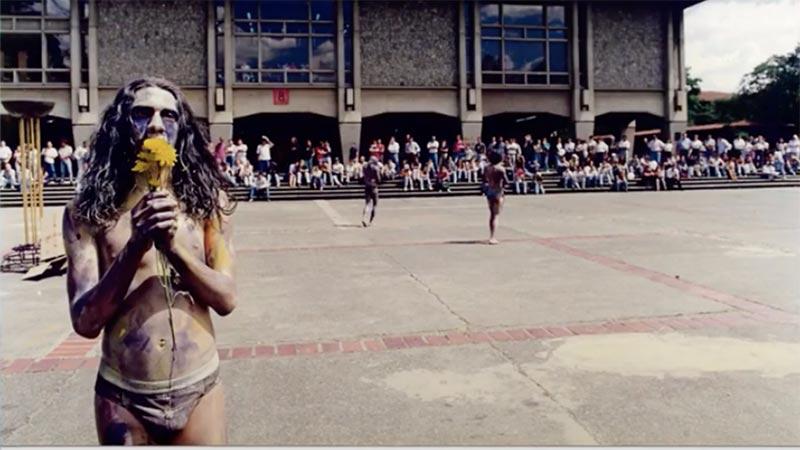 Una persona al frente de la biblioteca de la Universidad de Antioquia haciendo un performance